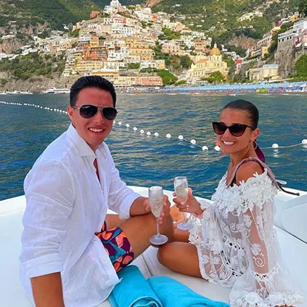 A couple enjoying a prosecco toast on the bow of a private yacht charter during a half day Amalfi Coast boat tour off the coast of Positano.