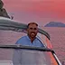 Captain Ivan Di Palma smiling at the helm of a private charter boat during a sunset cruise along the Amalfi Coast
