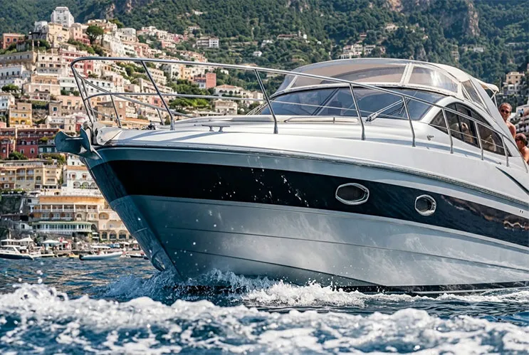 A dynamic close-up, low-angle view of a luxury Pershing motor yacht cruising past the colorful cliffside houses of Positano during a private Amalfi Coast boat tour.
